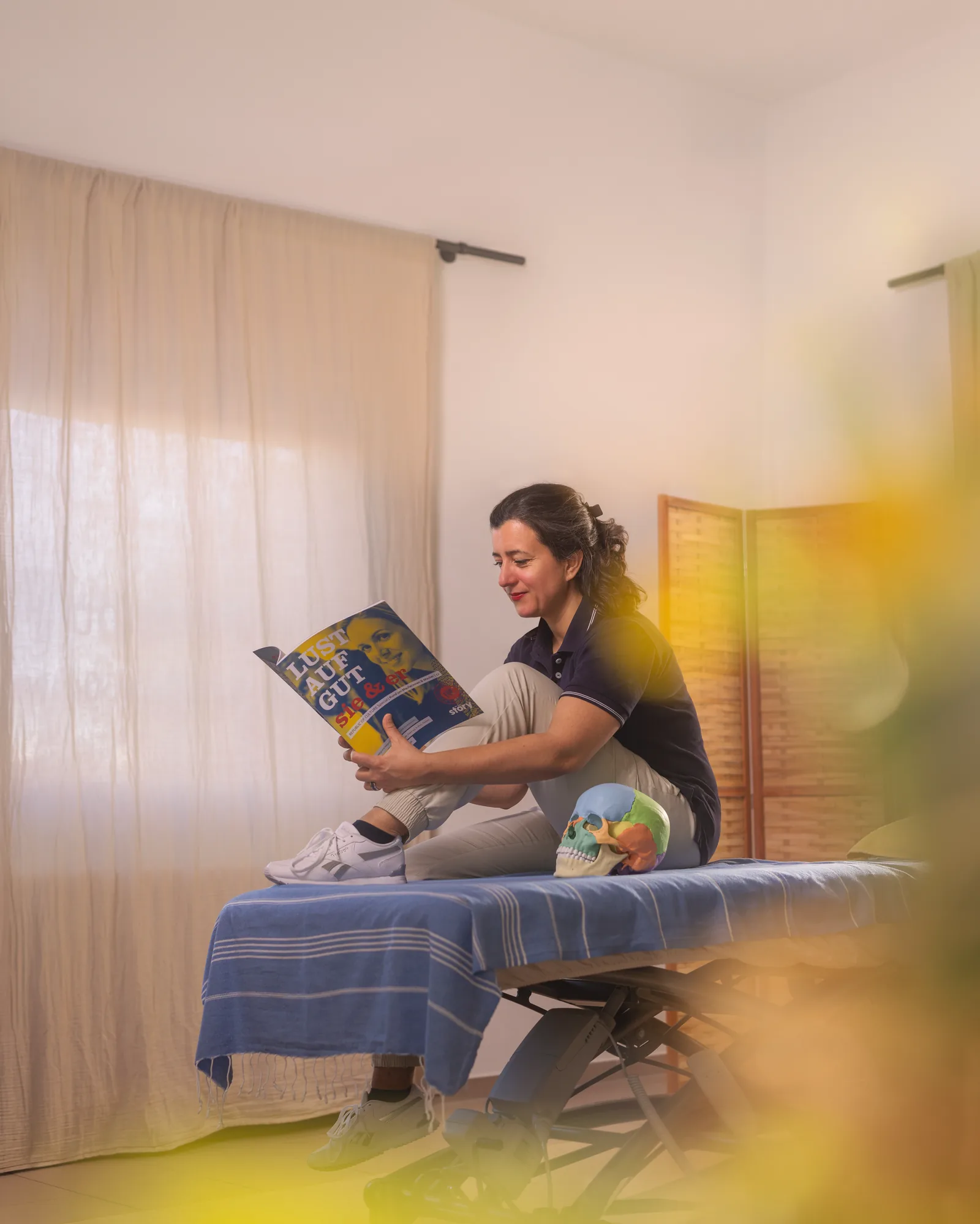 Nadine Winter sitzt in ihrer Praxis und liest ein Magazin